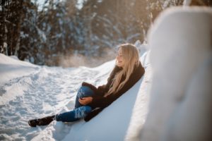 Новогодняя фотосессия на улице. Девушка лежит на снегу, красиво подсвечено дыхание естественным светом.